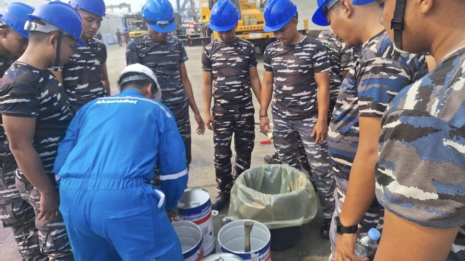 Yunara's International Paint technician showing the KRI Sriwijaya-100 crew how to mix Interlac 665 on the quay in Jakarta